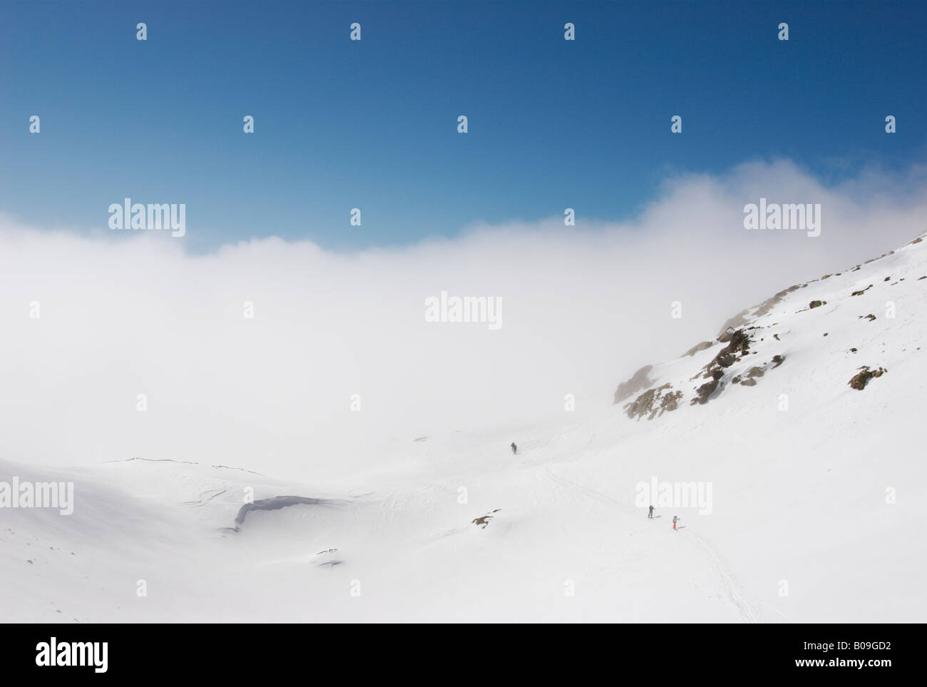 Gruppo di sciatori avvicinando Col Cicle su una soleggiata giornata invernale al di sopra delle nuvole, Les Contamines-Montjoie, Francia Foto Stock