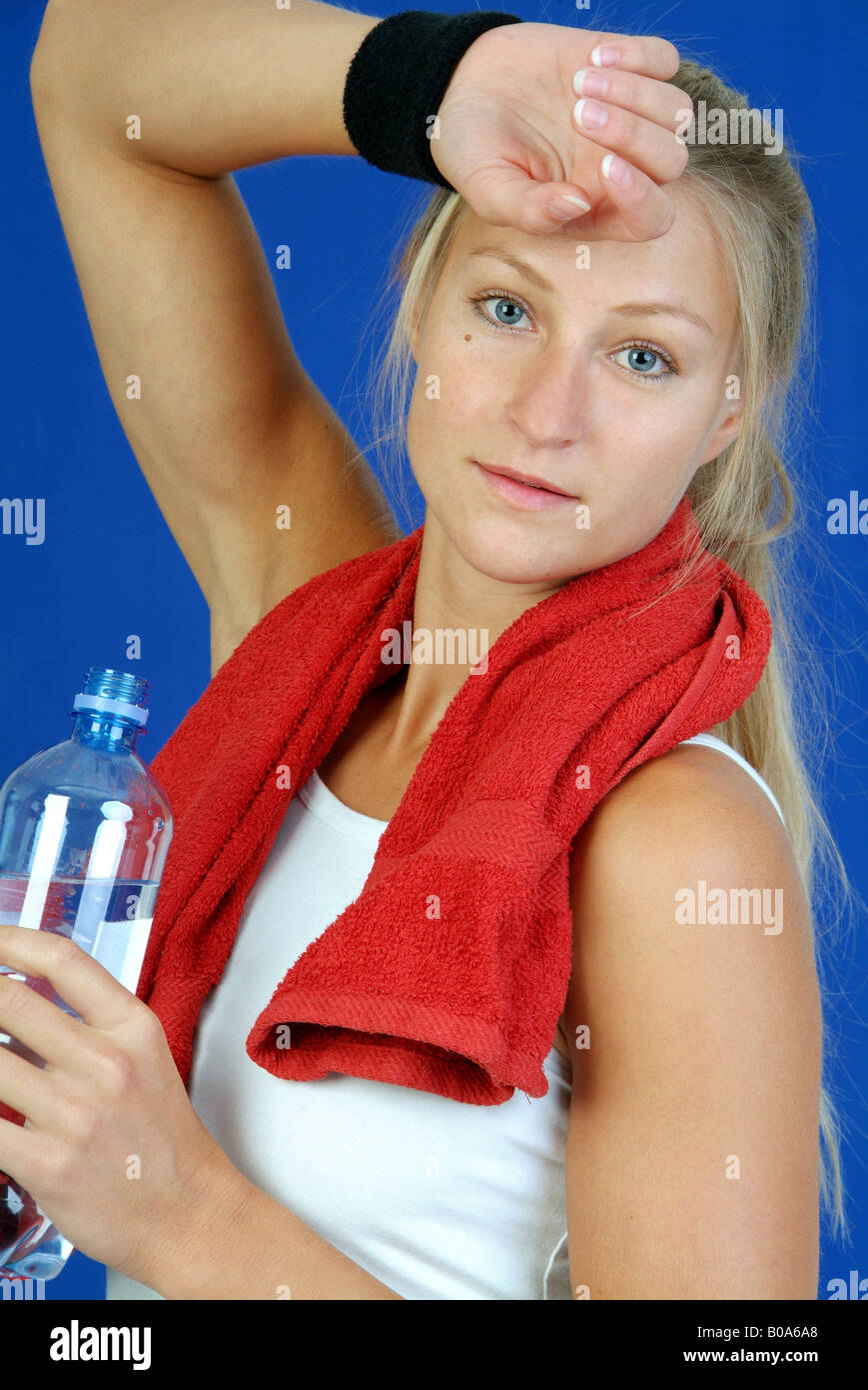 Usurati donna bionda con una bottiglia d'acqua e asciugamano rosso dopo il corso di formazione Foto Stock