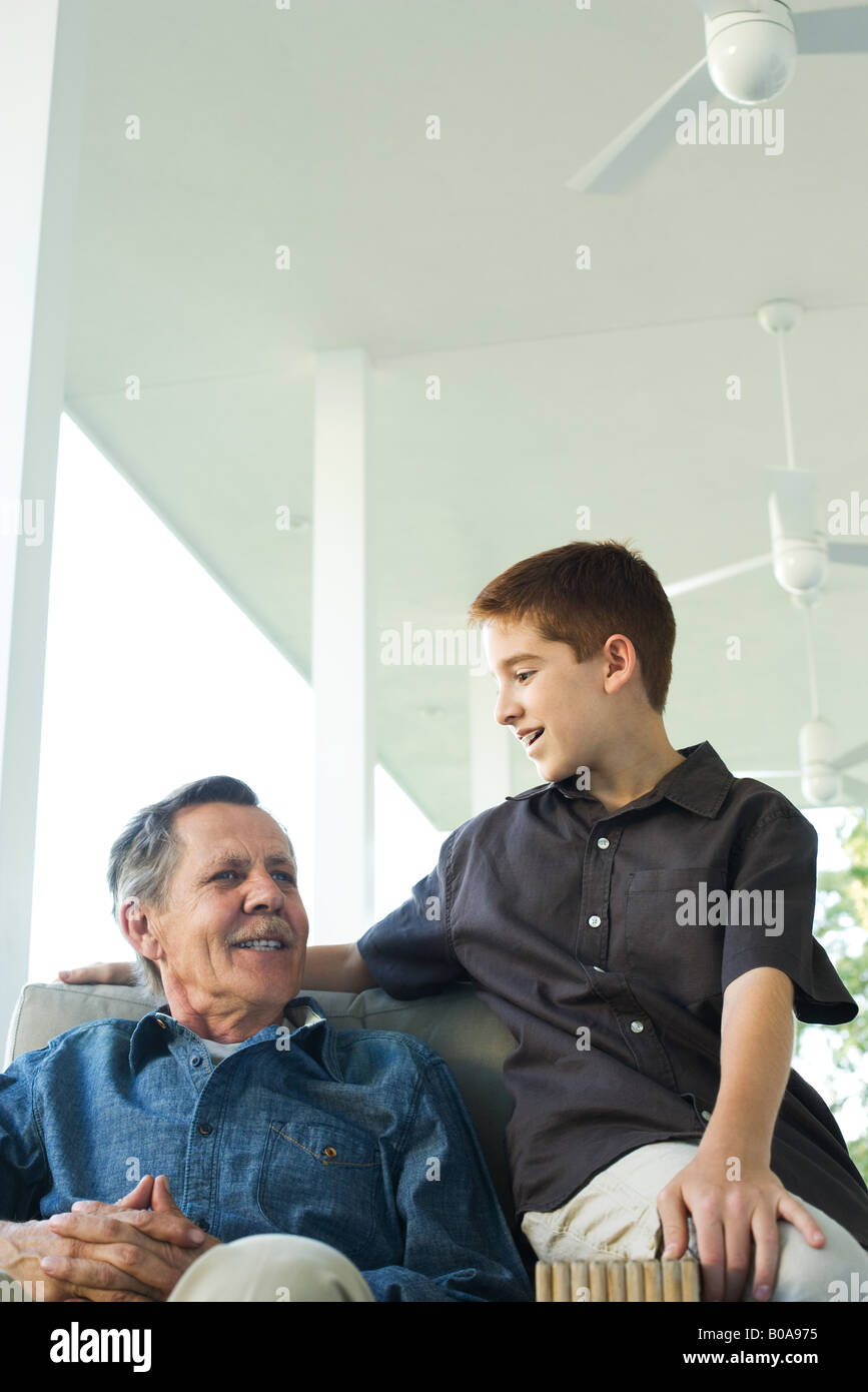 Nonno e nipote seduti insieme sul portico, entrambi sorridente Foto Stock