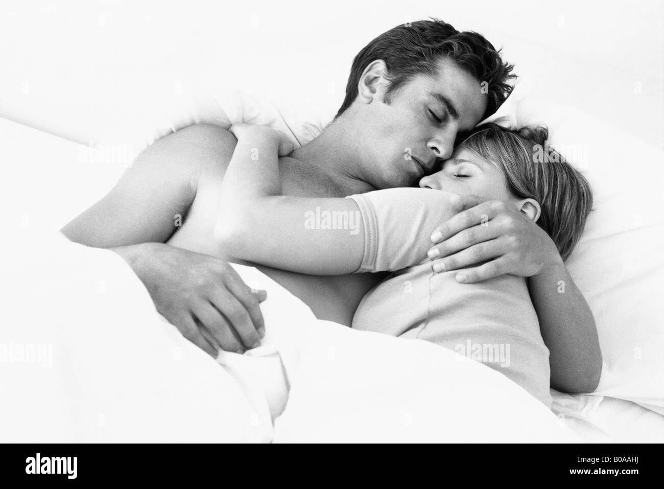 Giovane abbracciando nel letto a occhi chiusi Foto Stock