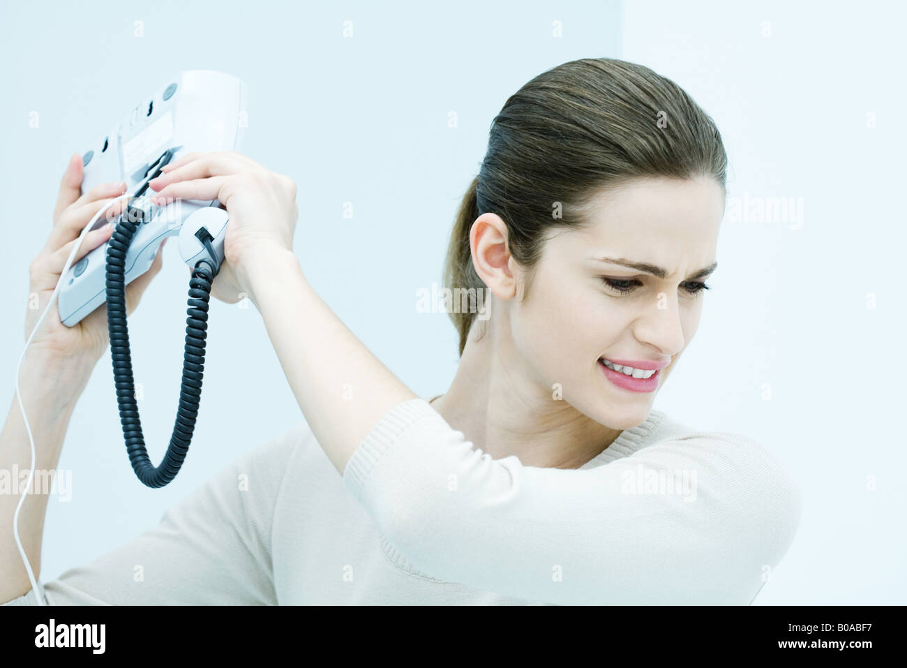 Giovane donna gettando telefono su rete fissa Foto Stock