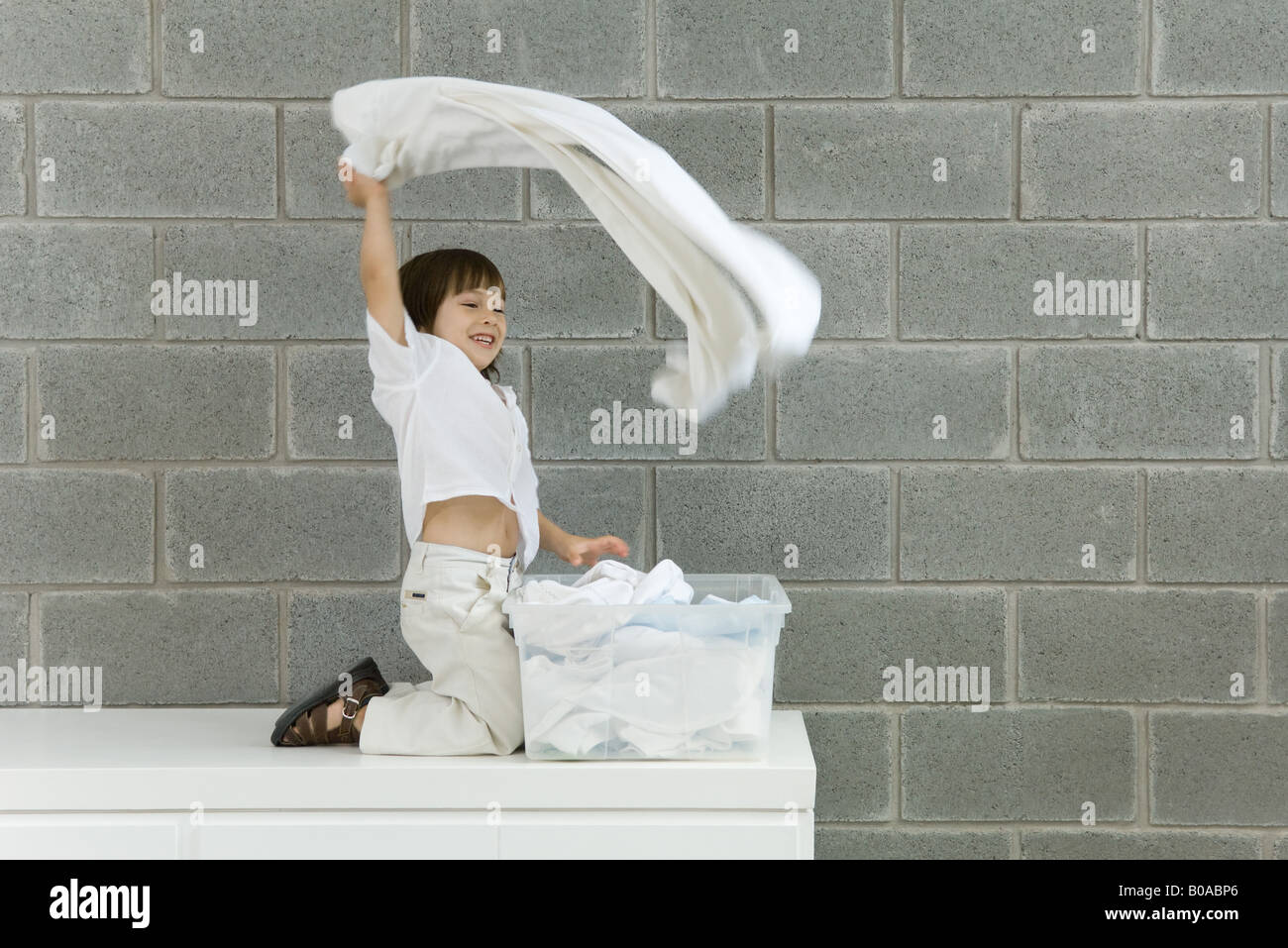 Little Boy giocando con lavanderia, sorridente, vista laterale Foto Stock