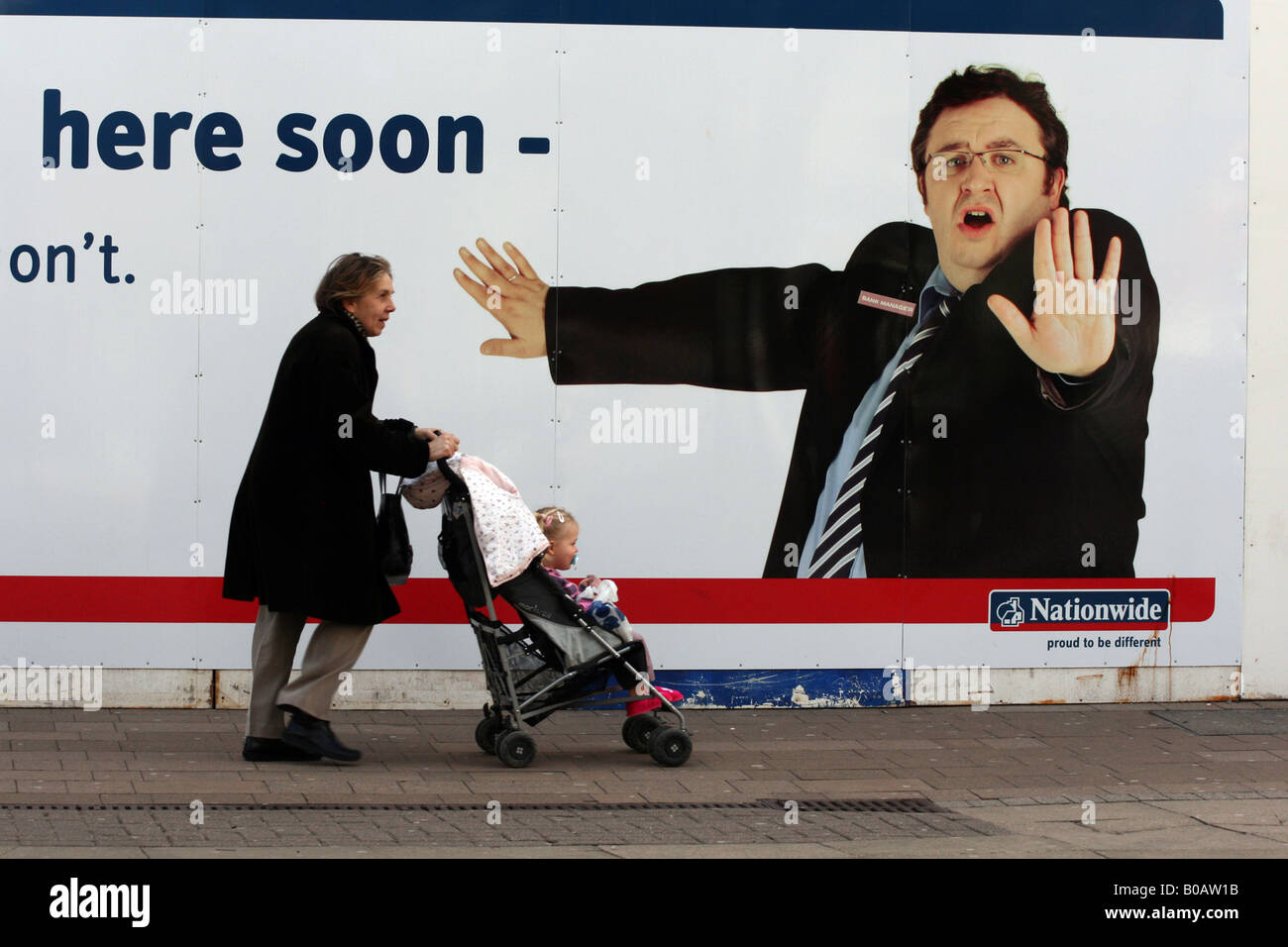 Donna spingendo la PRAM durante la deambulazione passato una banca nazionale poster pubblicitario nel Regno Unito. fotografia DON TONGE Foto Stock