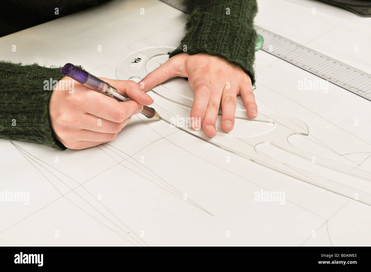 Giovane donna disegna una curva utilizzando un righello francese curva in altuglass, vetro acrilico. Foto Stock