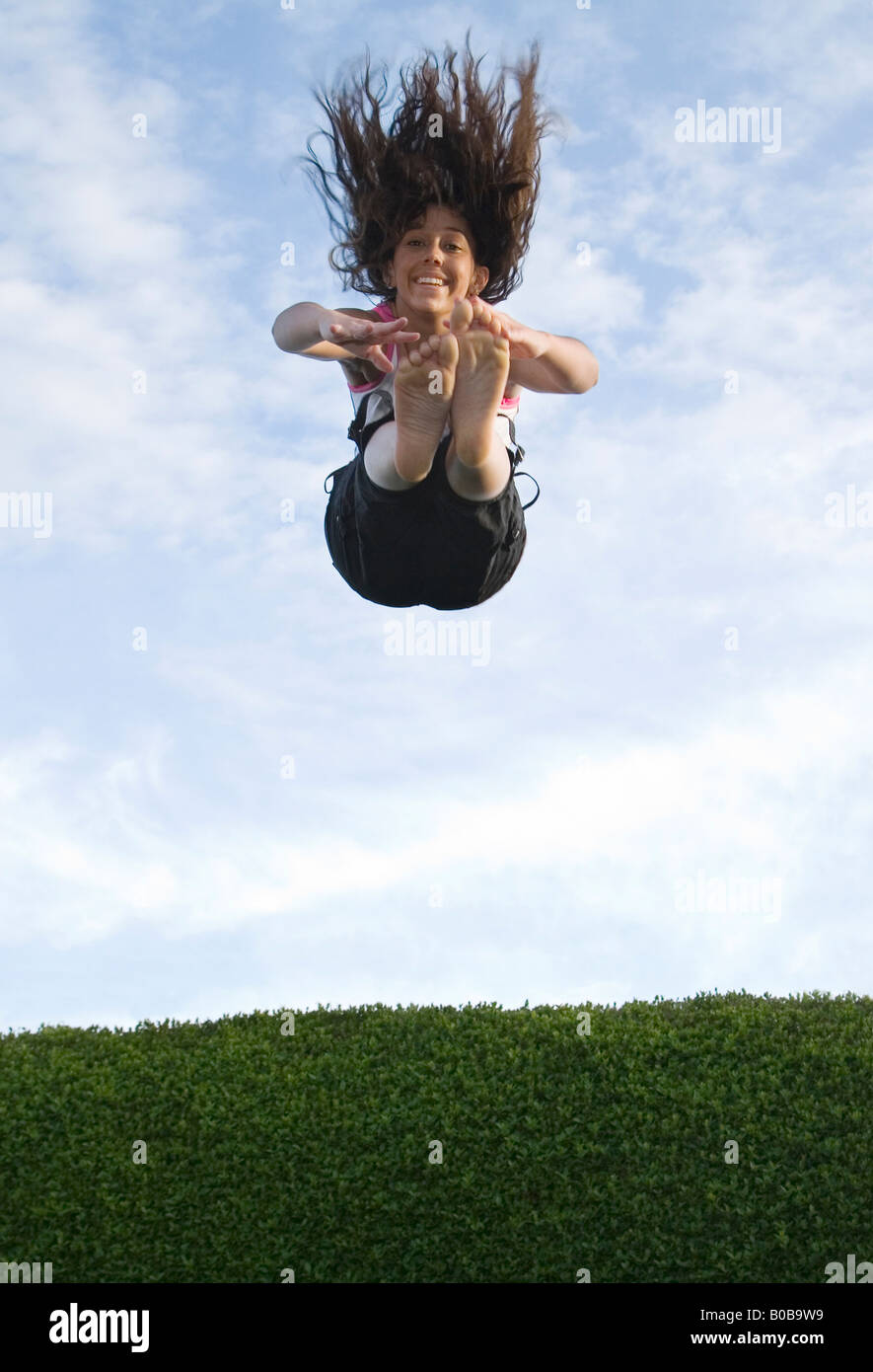 Una ragazza adolescente di salto e scendendo su un trampolino, REGNO UNITO Foto Stock