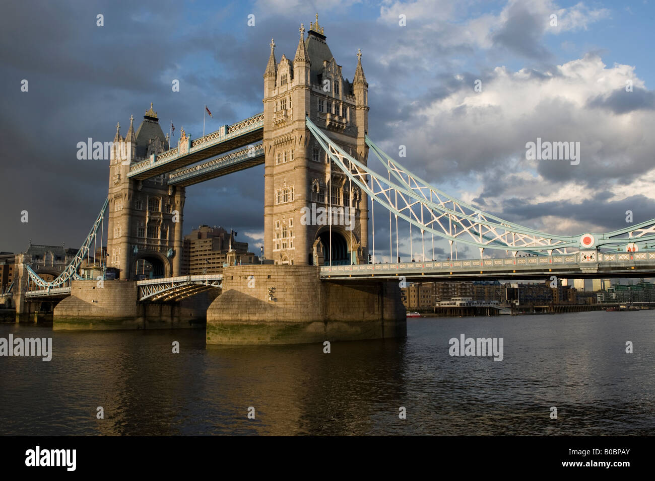 Il Tower Bridge di Londra illuminato da una forte luce del sole serale attraversa il fiume Tamigi Foto Stock