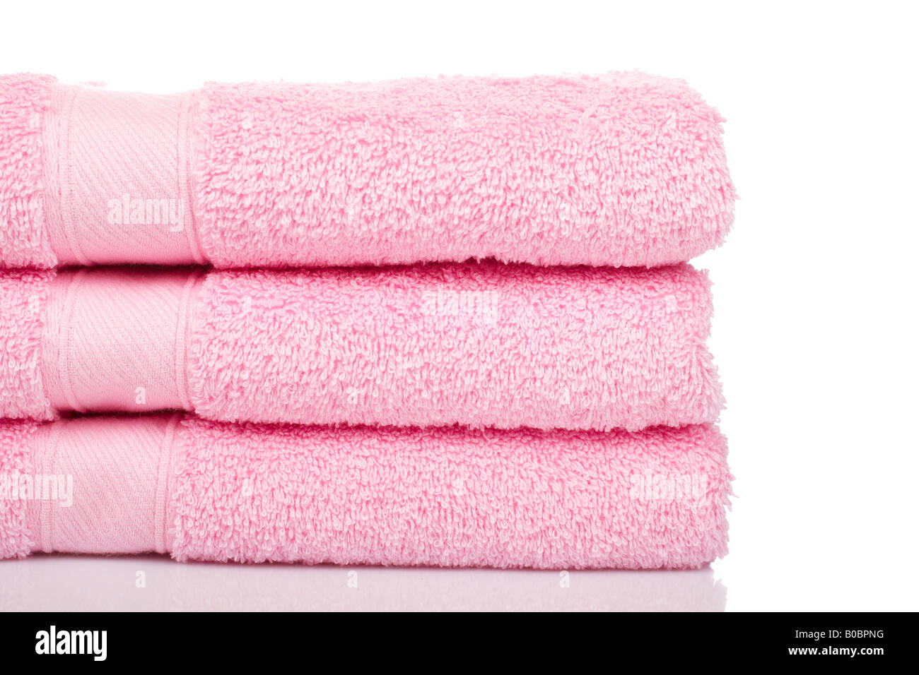 Un asciugamani rosa impilati riflette su sfondo bianco Foto Stock
