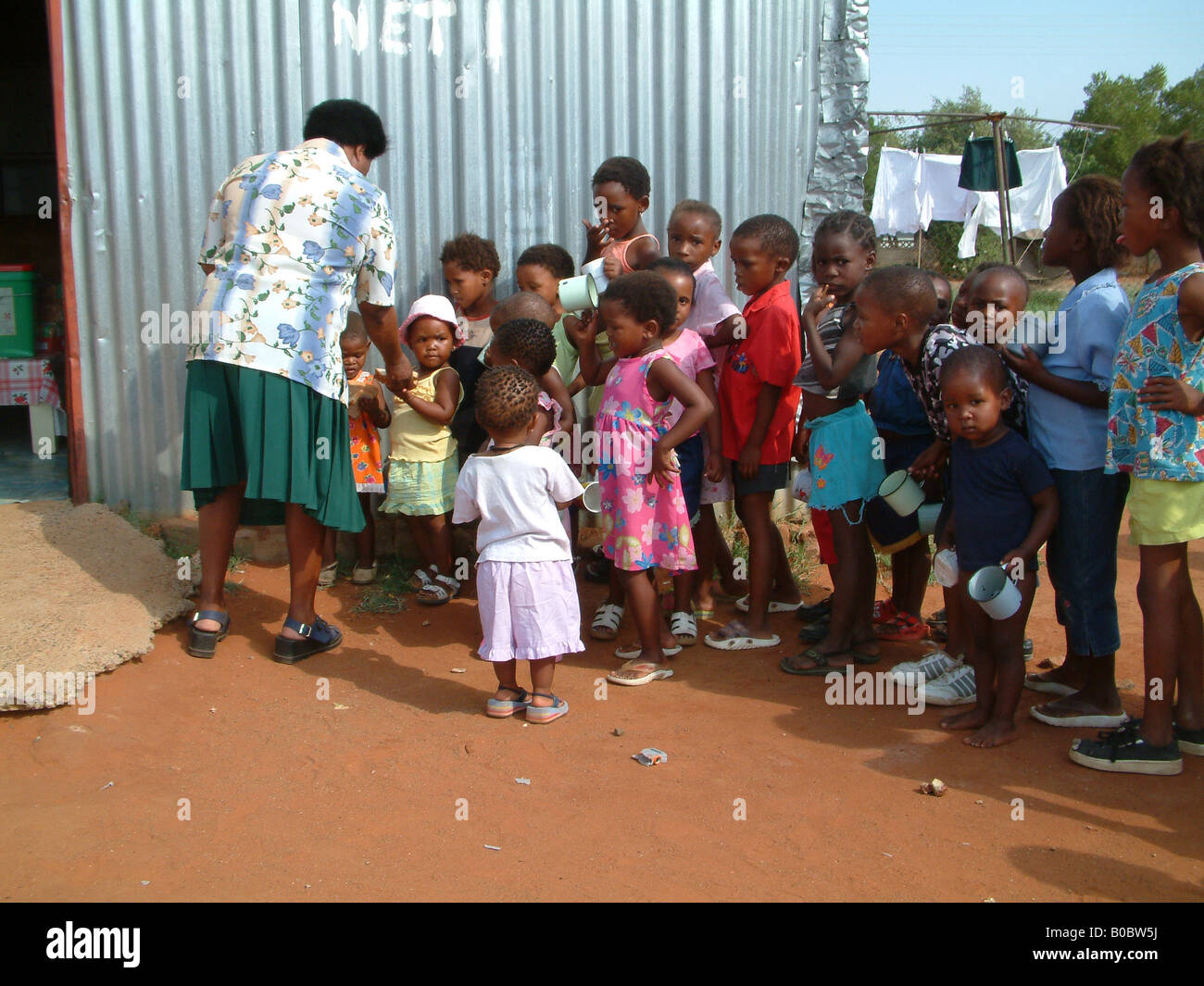 Miss Connie offre il pane e la minestra di bambini orfani Foto Stock