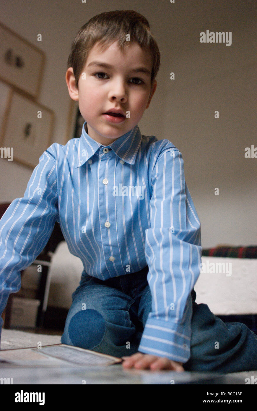 Sei anni vecchio ragazzo seduto sul pavimento Foto Stock