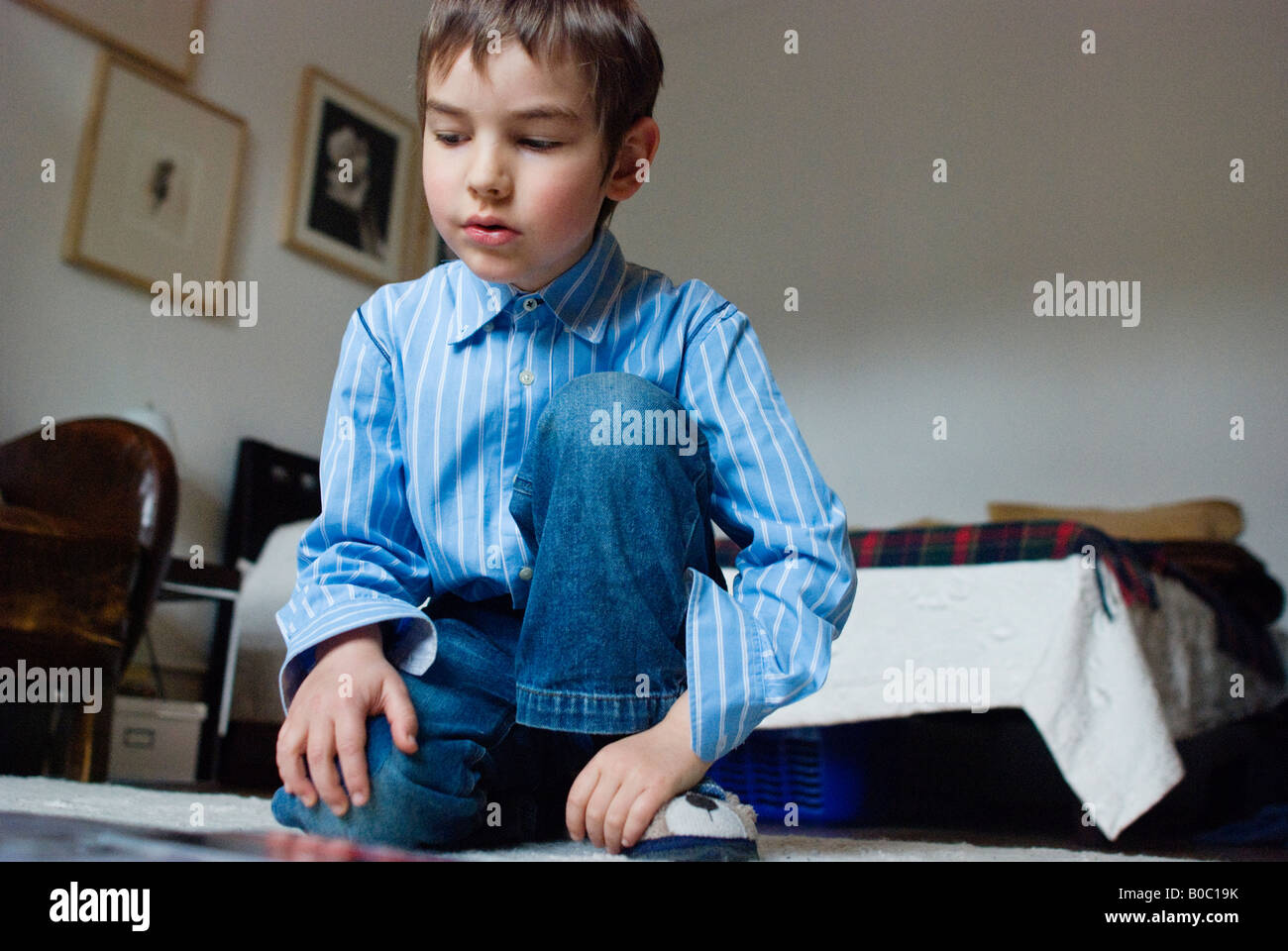 Sei anni ragazzo biondo si siede sul pavimento della camera la lettura di un libro Foto Stock