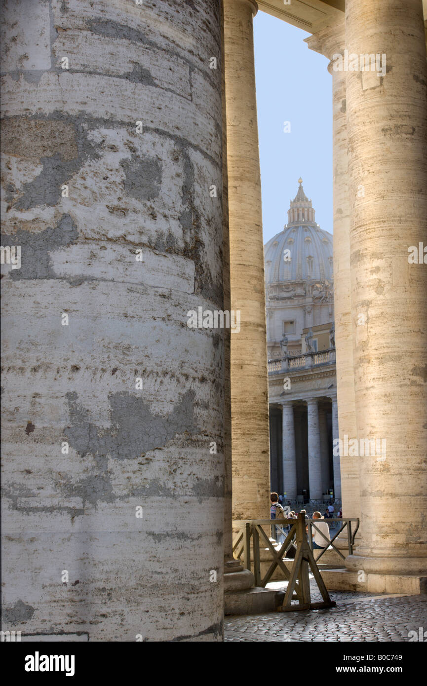 La basilica di San Pietro come intravisto attraverso i pilastri del colonnato del Bernini, che circonda la piazza di fronte alla chiesa Foto Stock