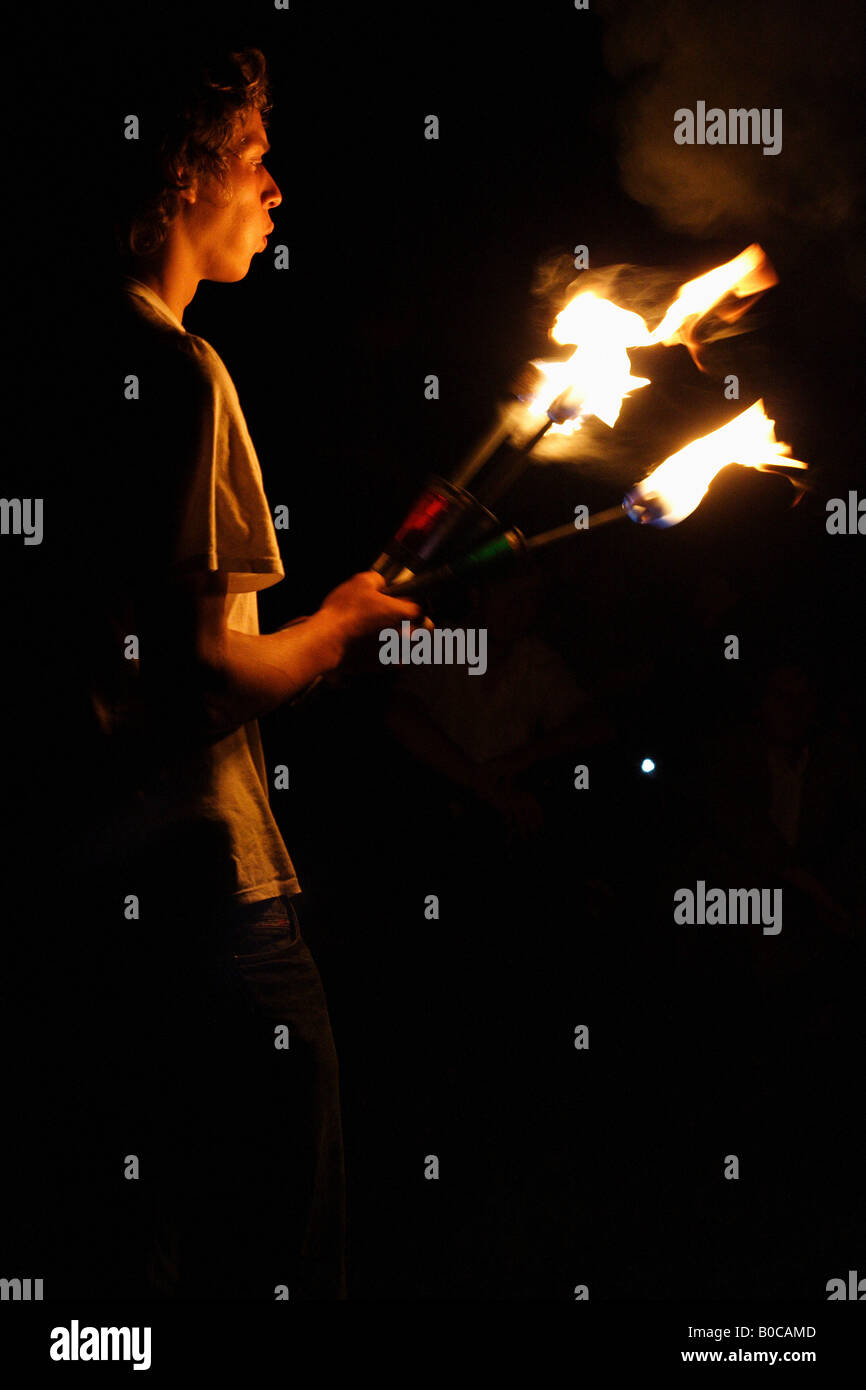 Giovane uomo giocoleria con fiaccole ardenti di notte Foto Stock