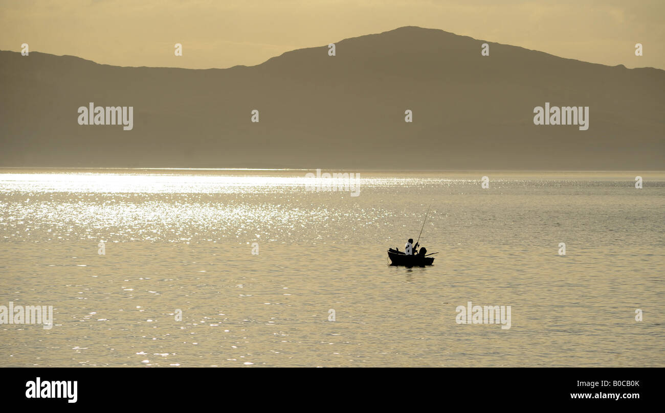 Un pescatore gode di una tarda sera VIAGGIO DI PESCA AL LARGO DELLA COSTA DELLA ISOLA DI JURA,NORD OVEST DELLA SCOZIA,UK Foto Stock