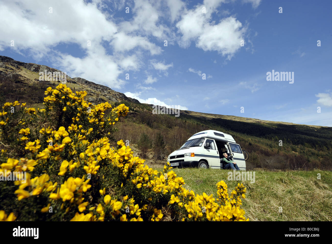 Una donna gode di clima soleggiato e la libertà di un camper vacanza nelle Highlands della Scozia.UK. Foto Stock