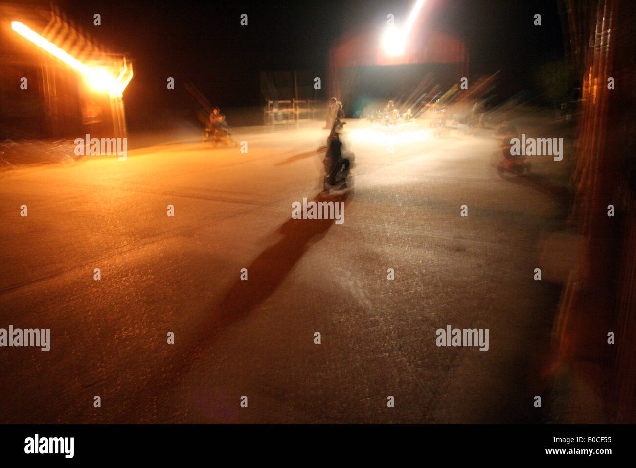 Altamente stilizzato pic dei bambini di notte a giocare su toy farm veicoli sotto le luci su di un calcestruzzo cantiere di fattoria Foto Stock