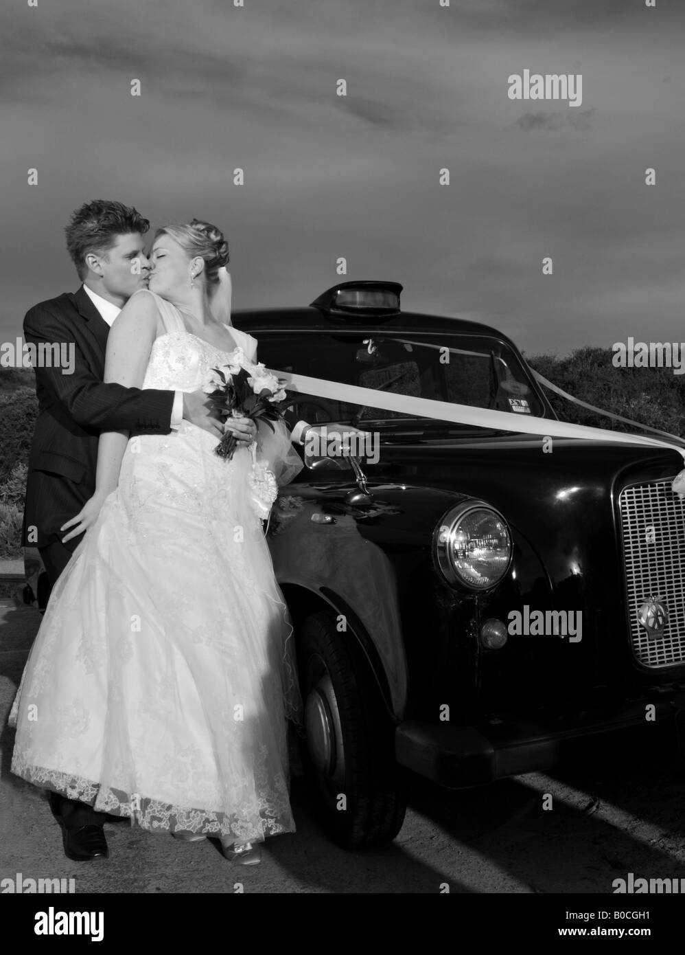 Sposa e lo sposo in piedi con le loro auto nozze kissing Foto Stock