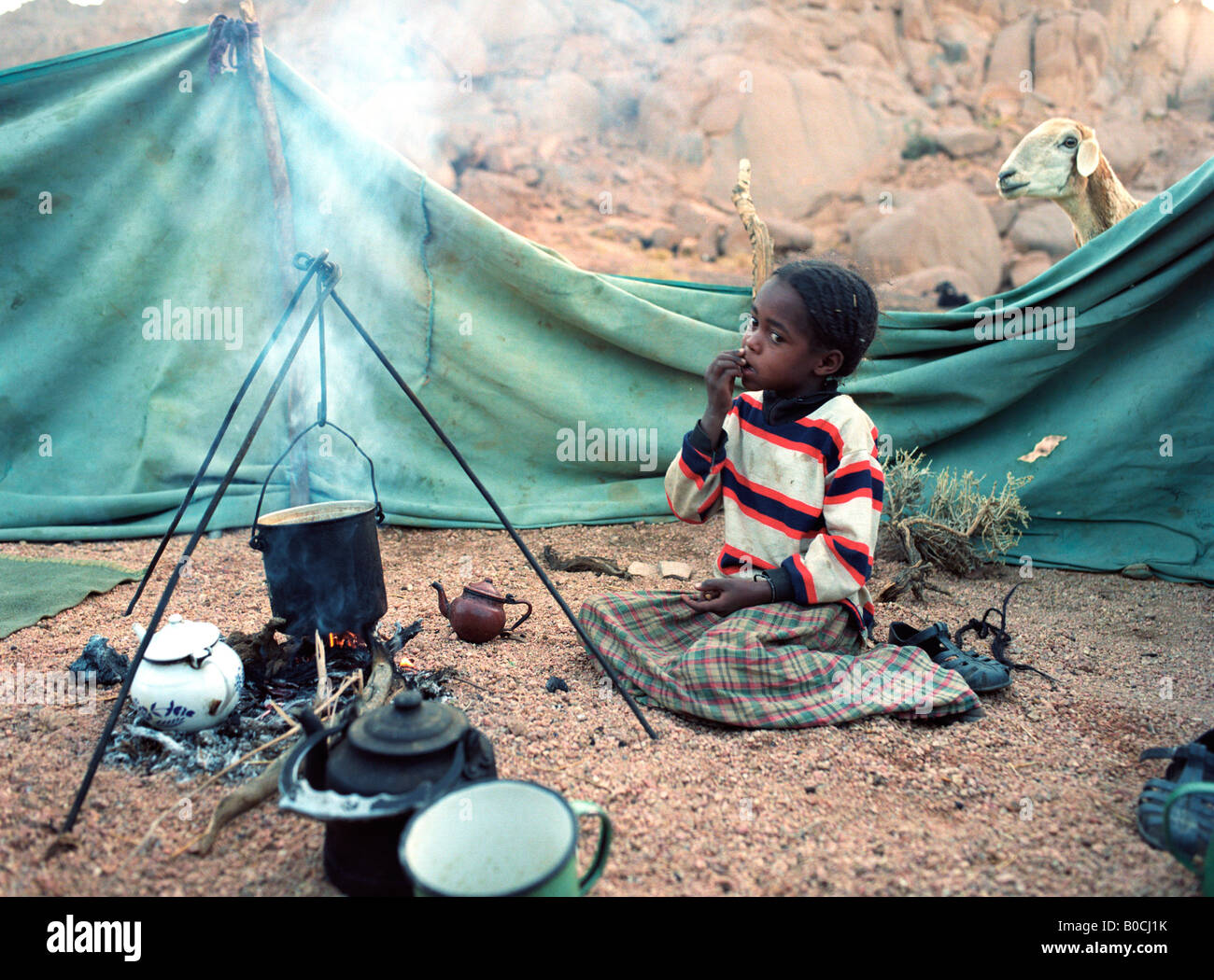 Una ragazza Tuareg è a guardia della pentola di cottura, preparare la colazione in un piccolo insediamento nel Ahaggar montagne del sud Algeria Foto Stock