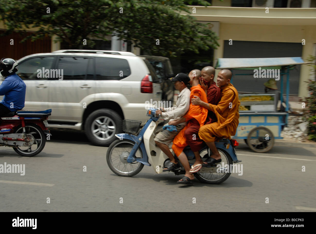 Un uomo e tre monaci su lo stesso moto in Phnom Penh Cambogia Foto Stock