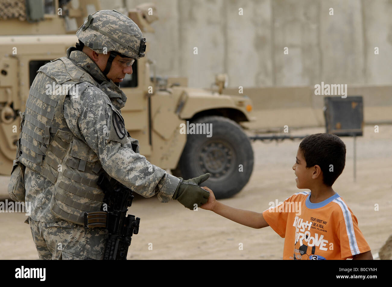 U S Army Maj Robert Rodriguez scuote le mani locale con un bambino durante una visita al mercato Taji in Iraq Foto Stock