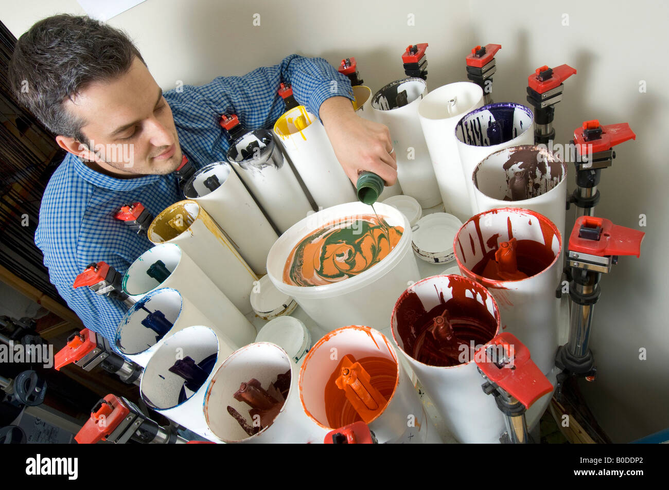 Un uomo per il mescolamento di vernici e colori di miscelazione in un workshop realizzazione su misura di vernice naturale per l'ordine. Foto Stock