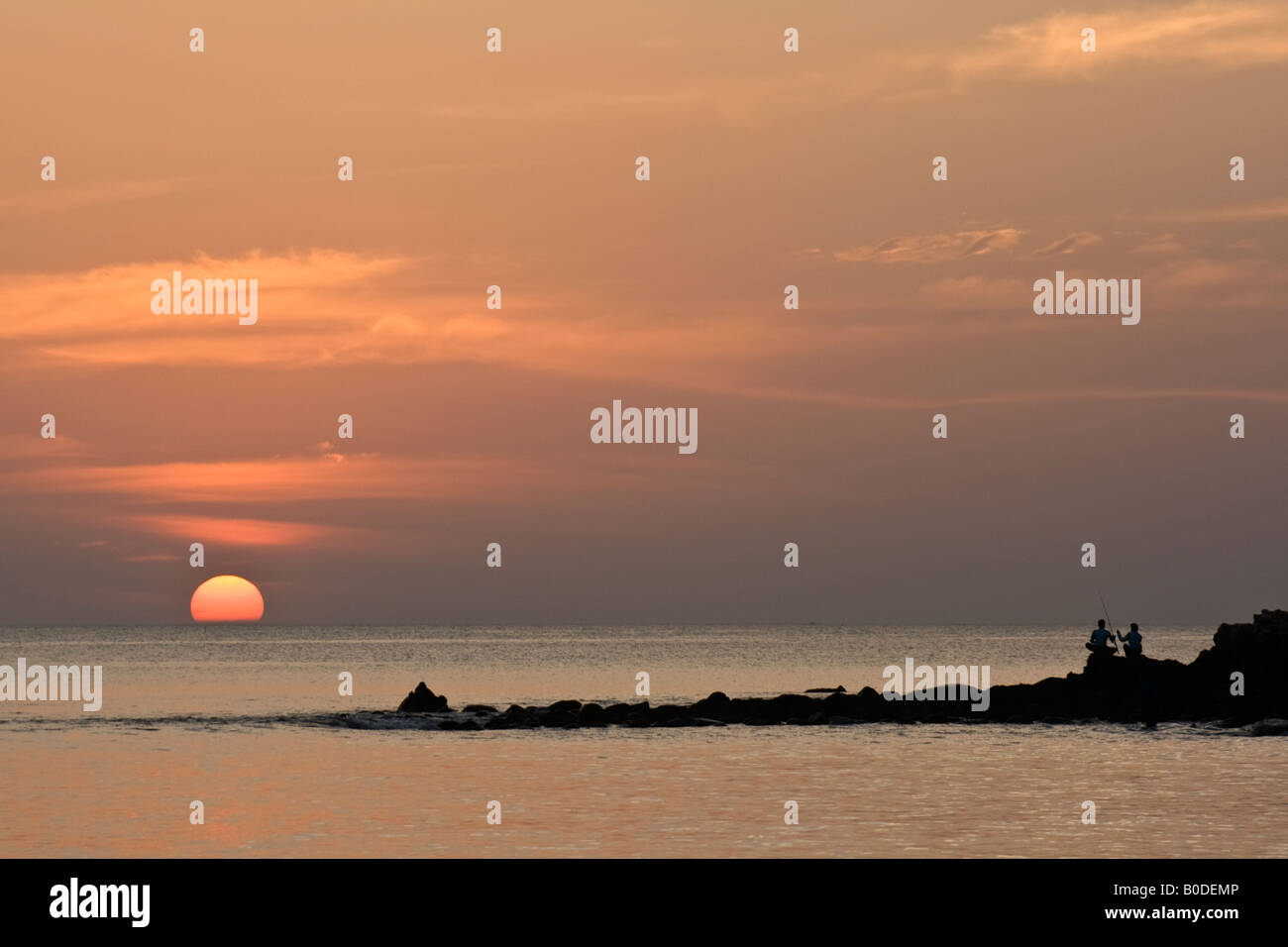 Tramonto a Phuket Beach con due persone di pesca su rocce thew Foto Stock