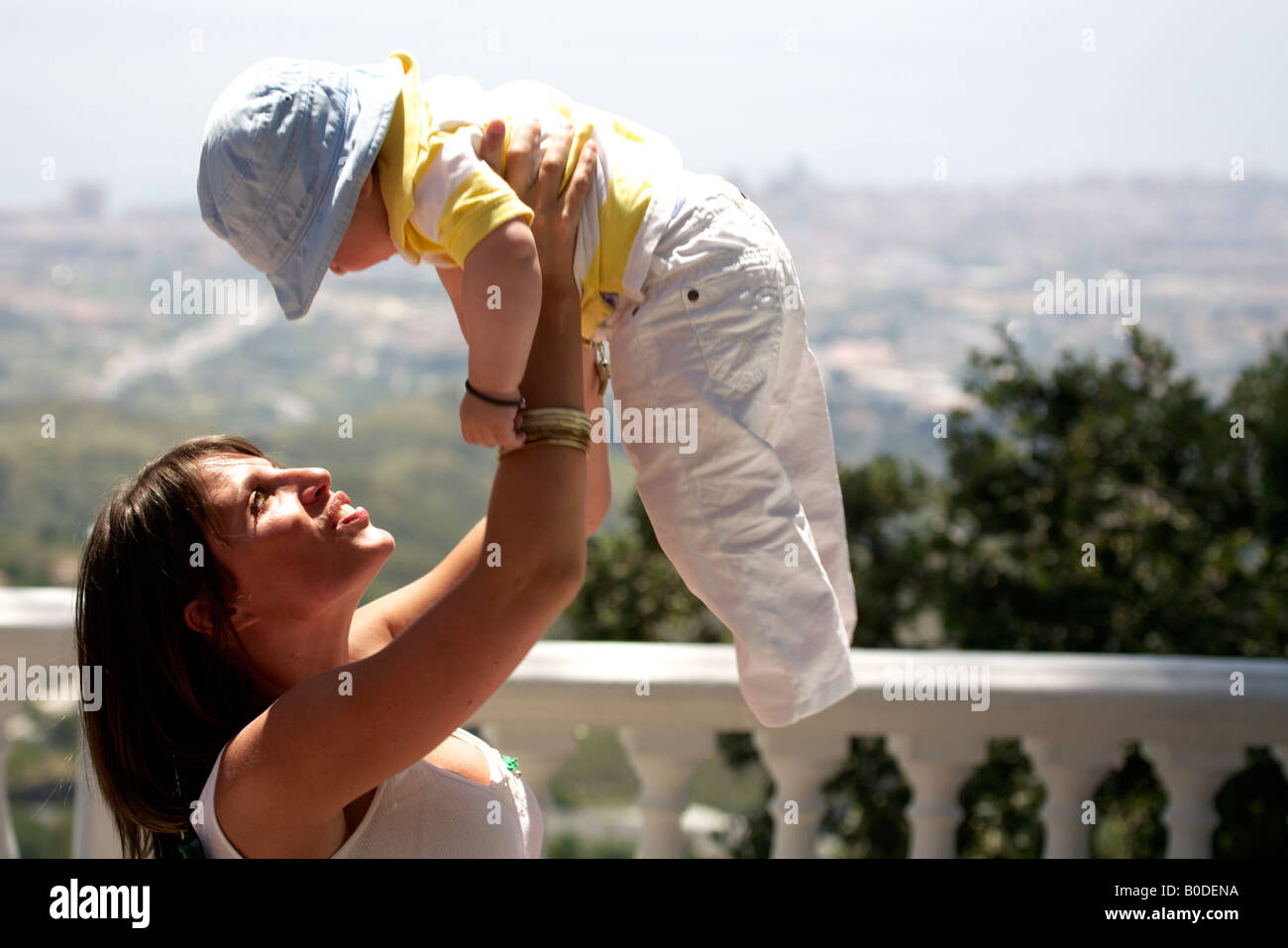 Giovane donna holding toddler sopra la sua testa a Mijas Pueblo, Costa del Sol, Andalusia, Spagna Foto Stock