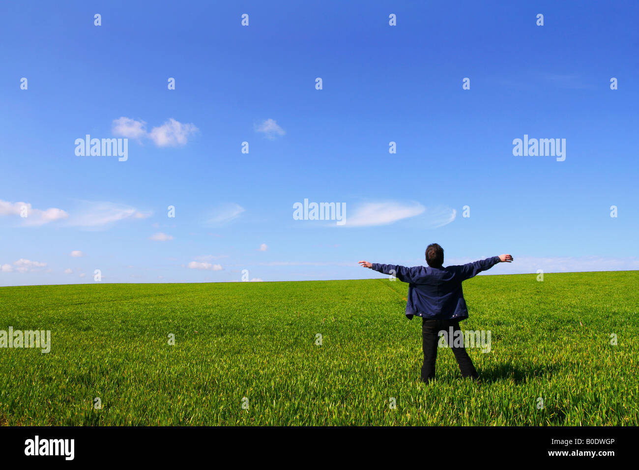 Un uomo solo in un campo verde respirare l aria con le braccia aperte Foto Stock
