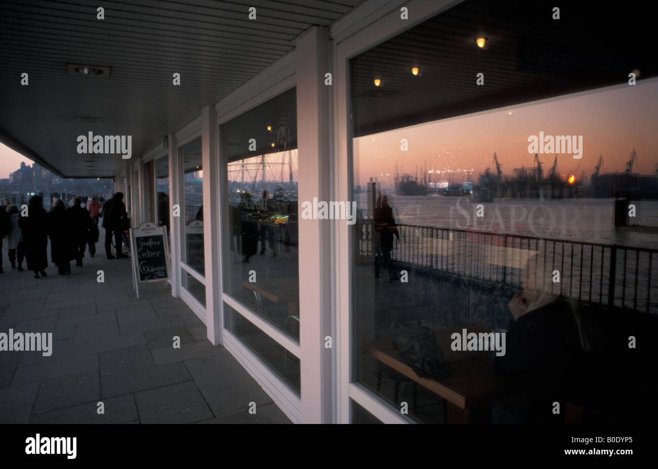 Le riflessioni dei Docks e porto nella finestra di un ristorante lungo la passeggiata del porto a Landungsbrueccken ad Amburgo, Germania Foto Stock