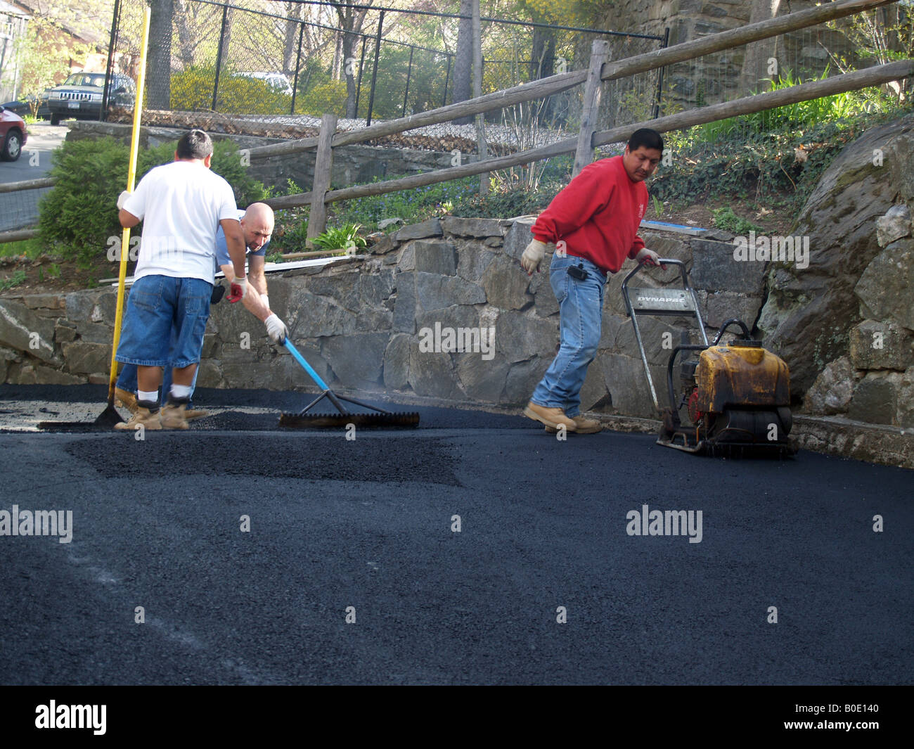 La diffusione dei lavoratori su asfalto appena costruito passo carraio Foto Stock
