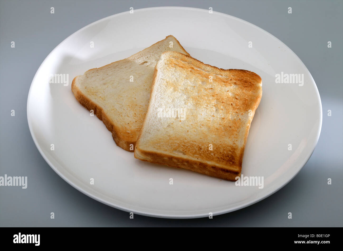 Bianco fresco tostare il pane su una piastra bianca nel sole di mattina a colazione che mostra di consistenza e di colore Foto Stock