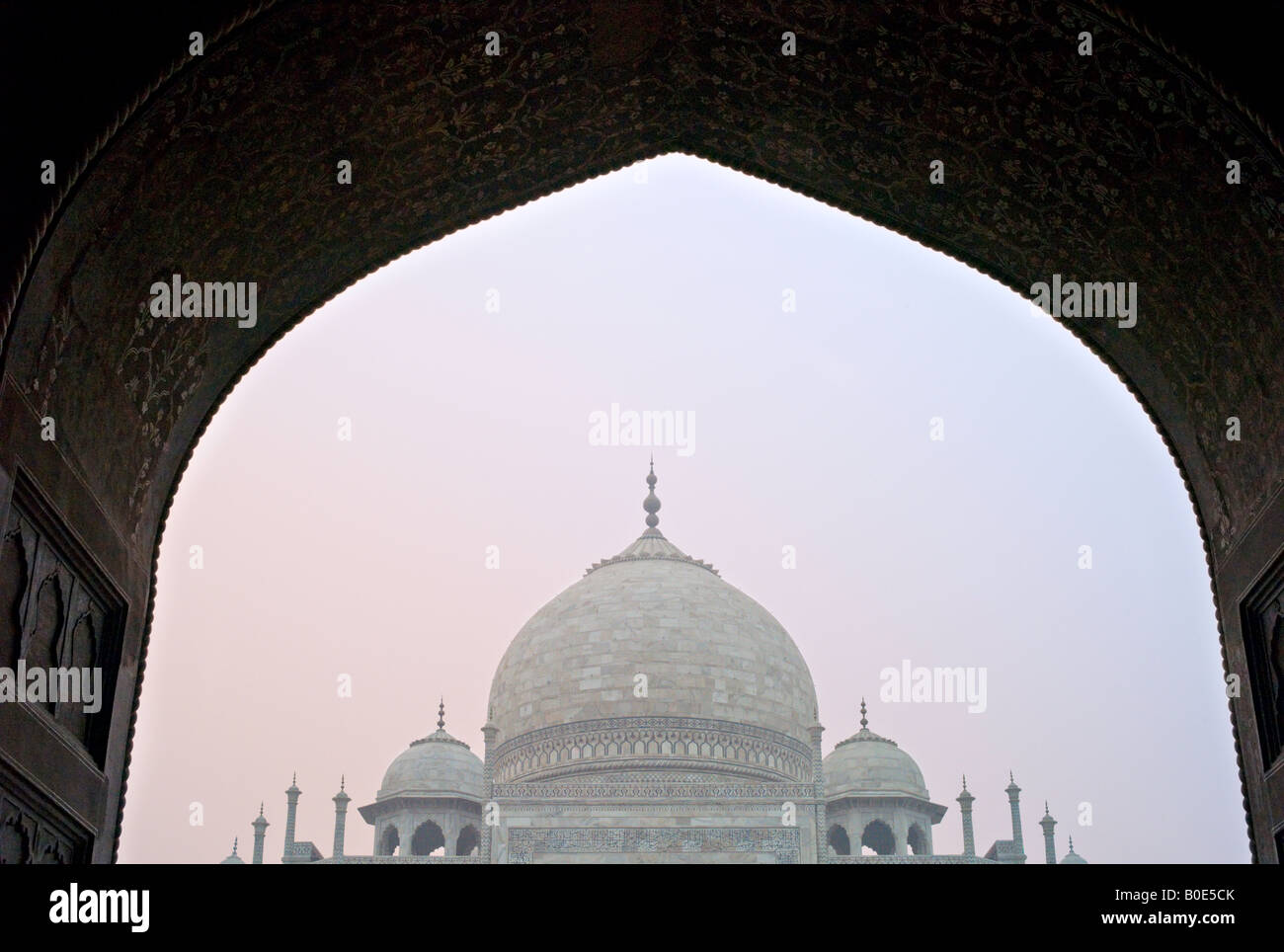 INDIA AGRA monumento del Taj Mahal si vede attraverso e riccamente decorate arco nella nebbia mattutina di sunrise Foto Stock