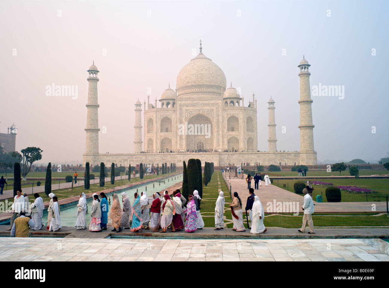 INDIA AGRA monumento del Taj Mahal si vede attraverso la nebbia di mattina a sunrise come le donne indiane in sari visita il sito UNESCO Foto Stock