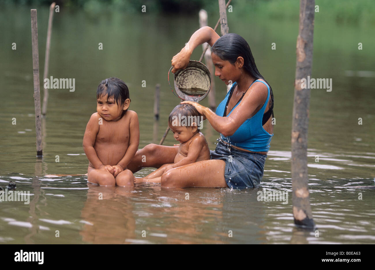 Povera donna lavando i suoi figli in Amazzonia fiume vicino a Santarem in Brasile Foto Stock