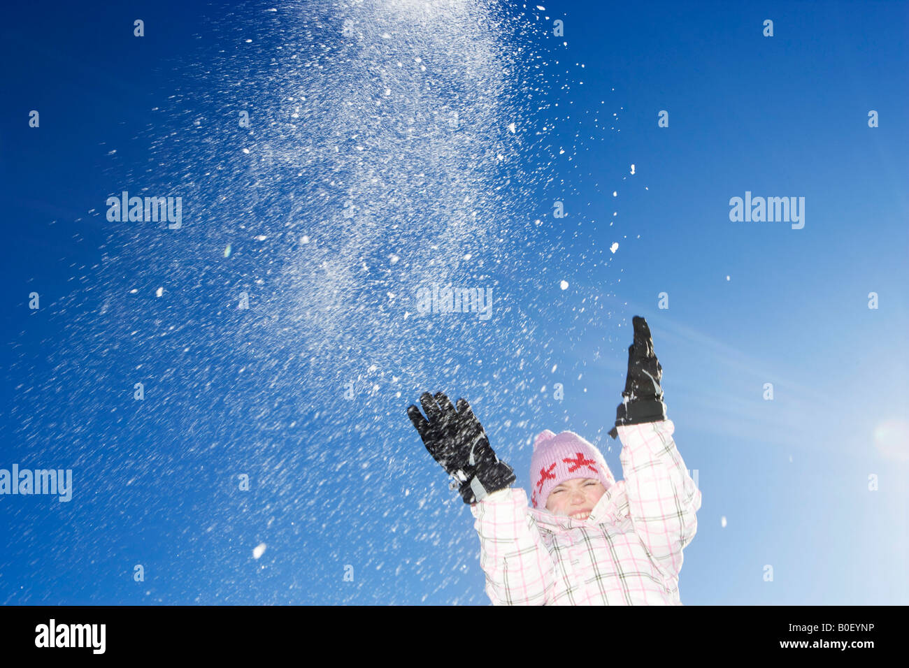 Giovane ragazza gettando la neve in aria Foto Stock