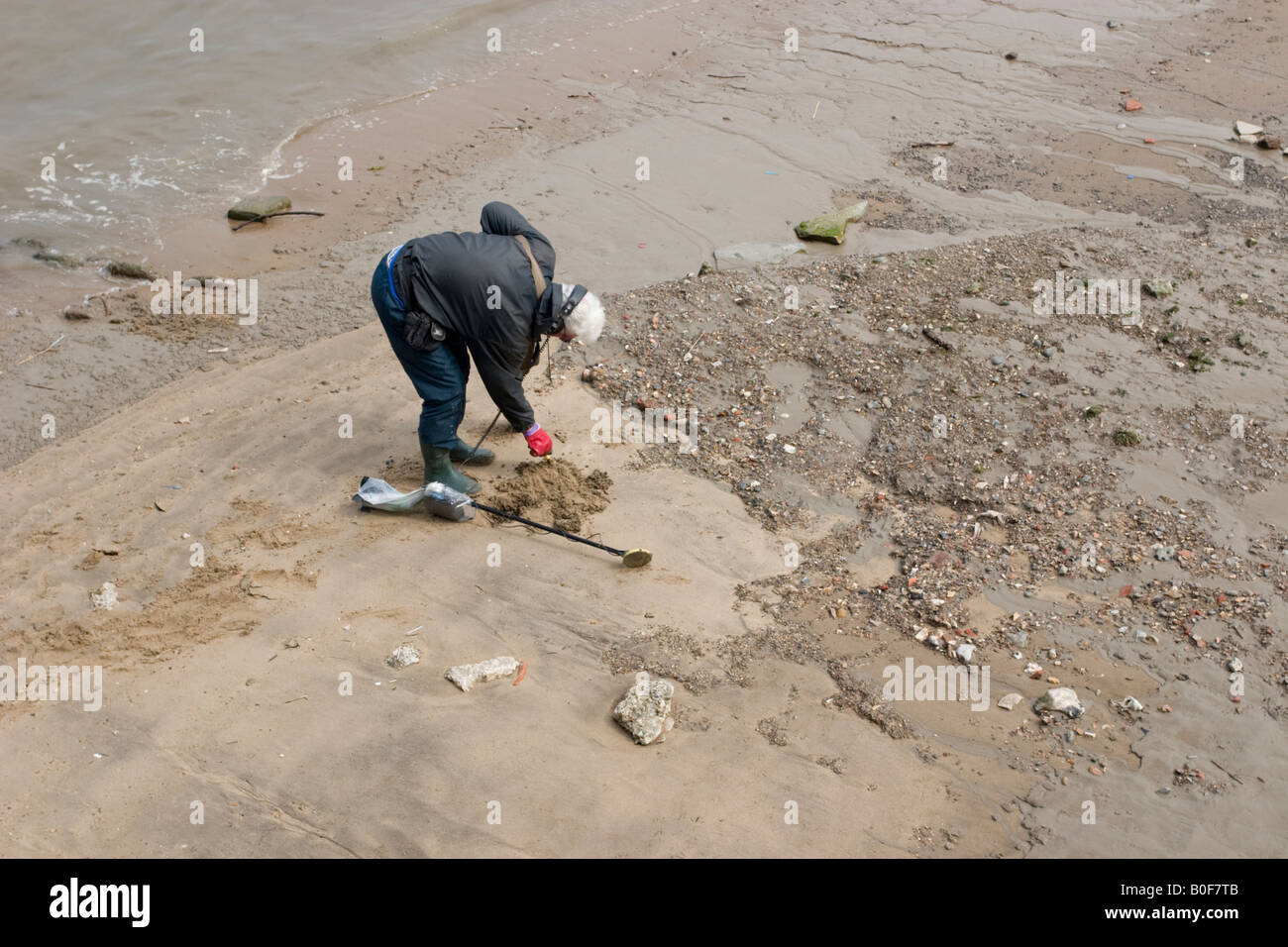 Metallo ricerche Detectorist il Foreshore vicino al Molo di Greenwich si piega per cercare una pila di sabbia più in dettaglio Foto Stock