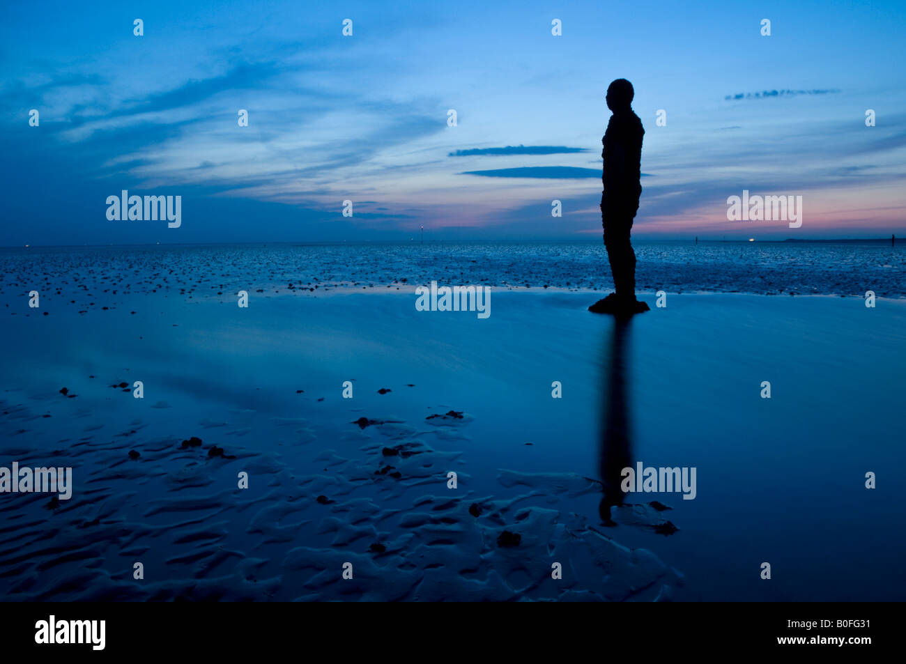 Antony Gormley è un altro posto statue al crepuscolo su Crosby Beach, Crosby, Merseyside England, Regno Unito Foto Stock