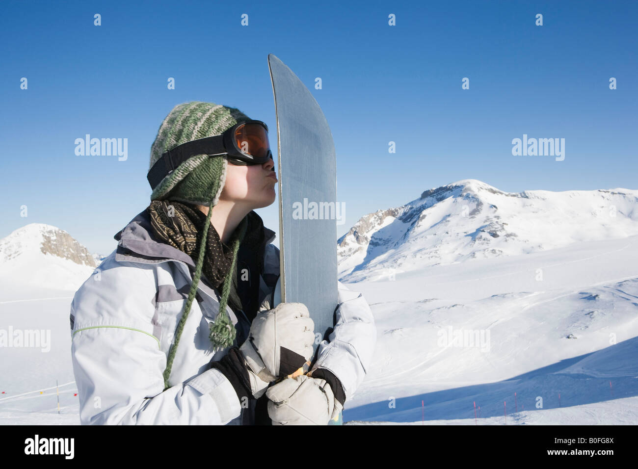 Snowboarder kissing snowboard Foto Stock