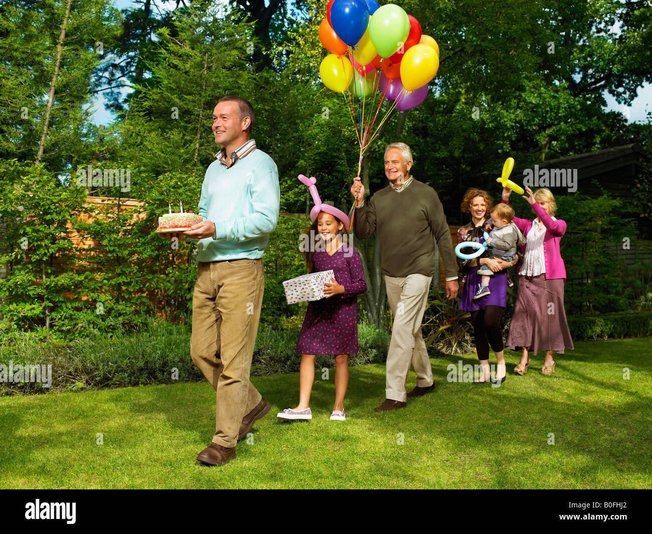 Famiglia in arrivo con torta di compleanno Foto Stock