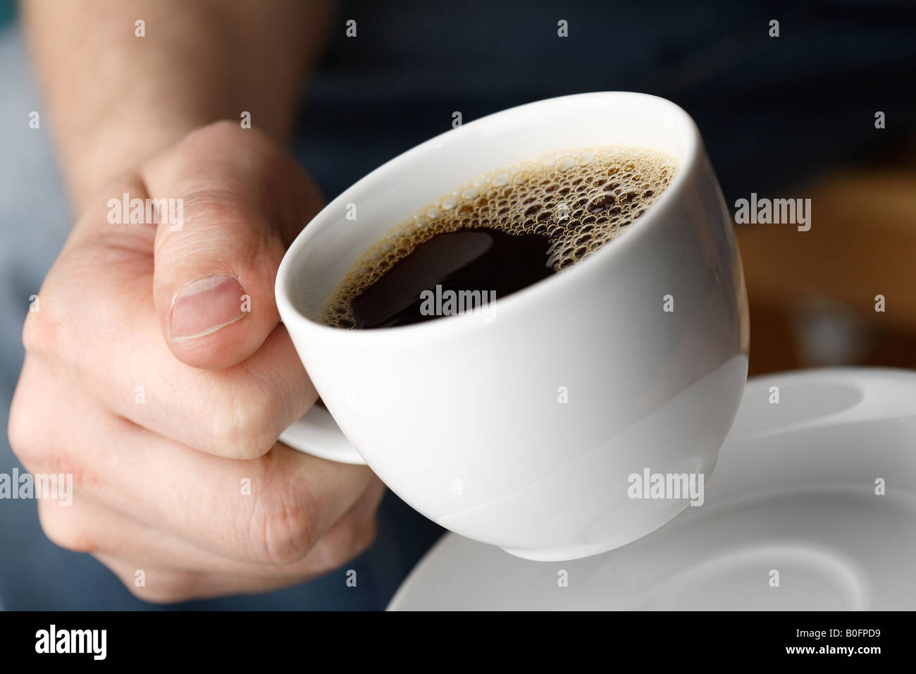 Mano con una tazza di caffè fresco Foto Stock