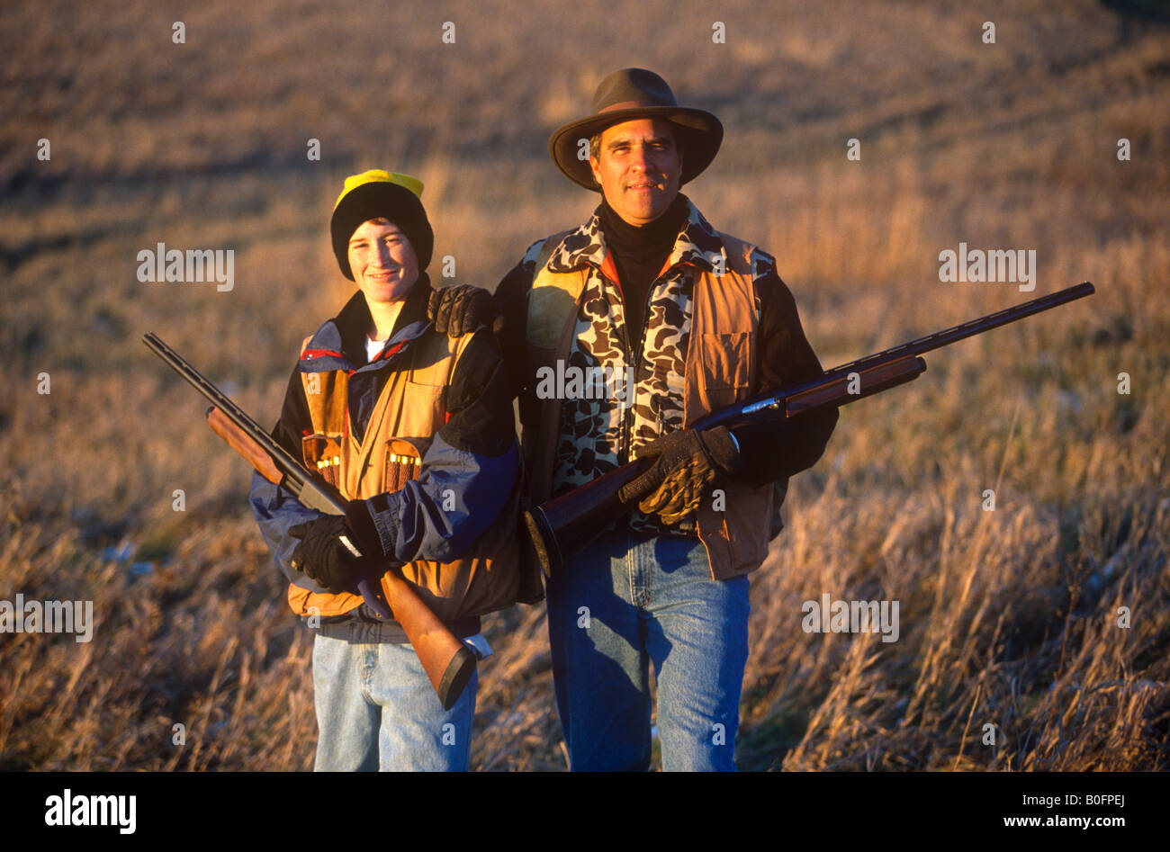 Un padre e figlio a caccia di uccelli in un campo erboso alla fine della giornata. Foto Stock