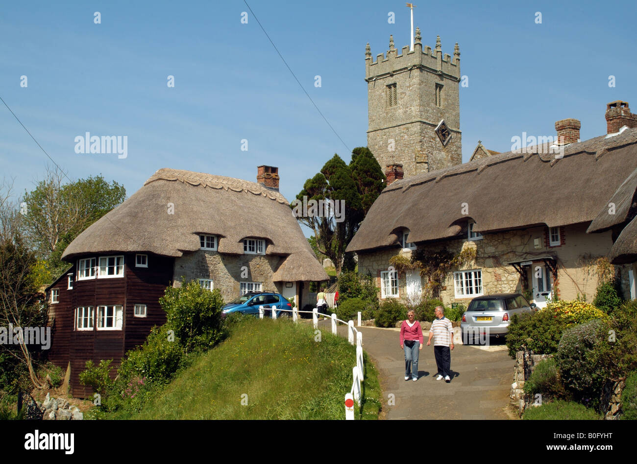 I turisti in visita a cottage con il tetto di paglia e chiesa a Godshill Isola di Wight in Inghilterra Foto Stock