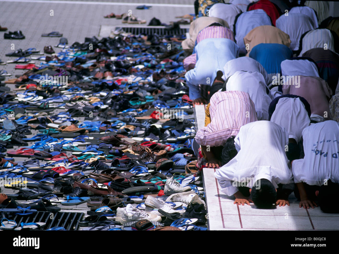 Pile di scarpe accanto a un gruppo di fedeli alla preghiera del venerdì, Malaysia. Foto Stock