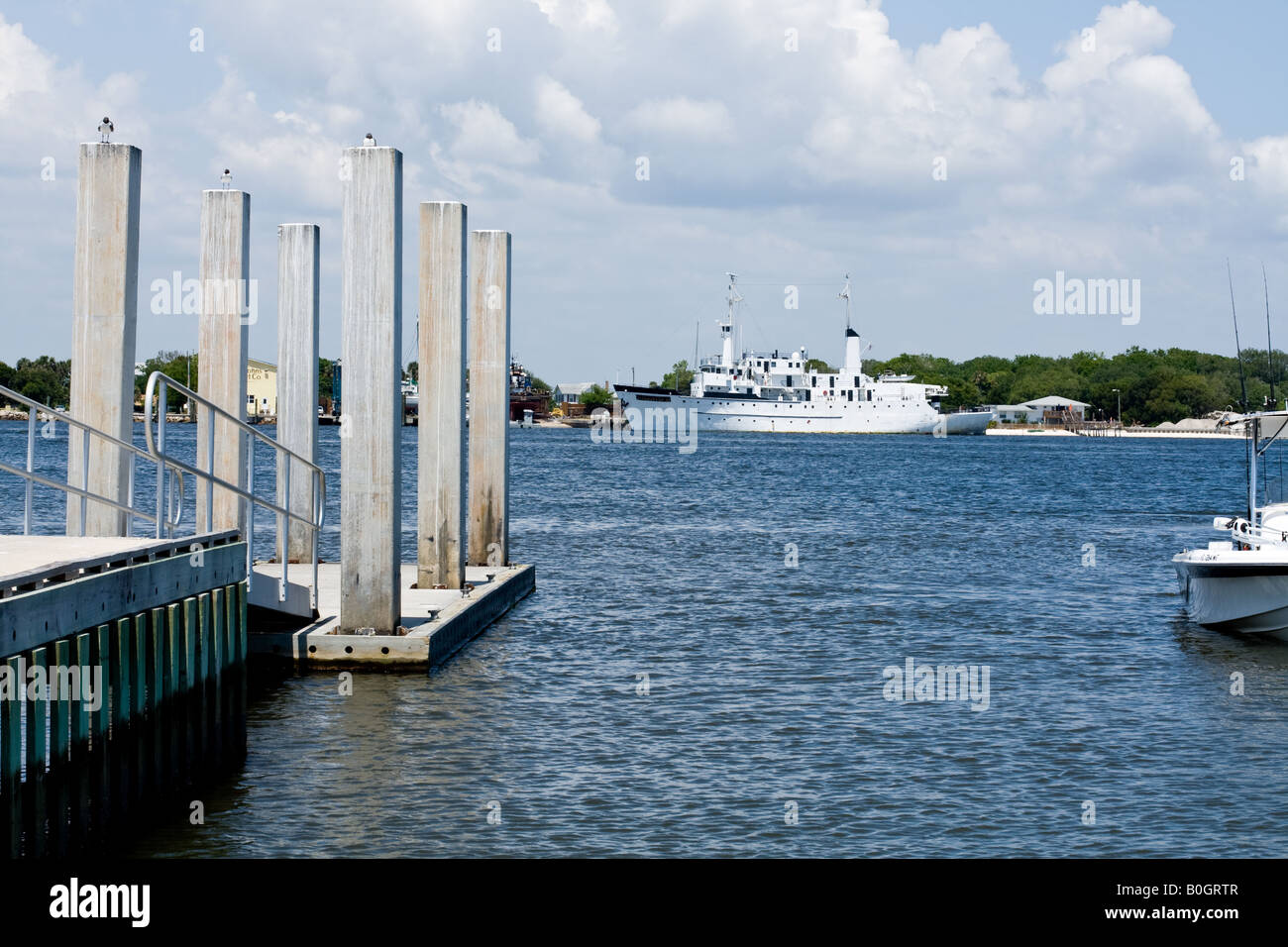 Palificazioni di cemento su una dock con uccelli arroccato sulla cima di una piccola nave da crociera in background in Mayport, Florida Foto Stock