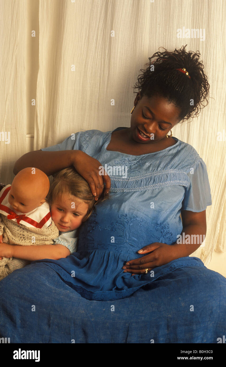 Etnia incinta Donna con bambina tenendo una bambola Foto Stock