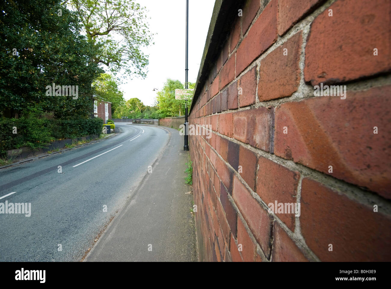 Ampio angolo di visione di un muro di mattoni su una strada che conduce l'occhio all'immagine Foto Stock