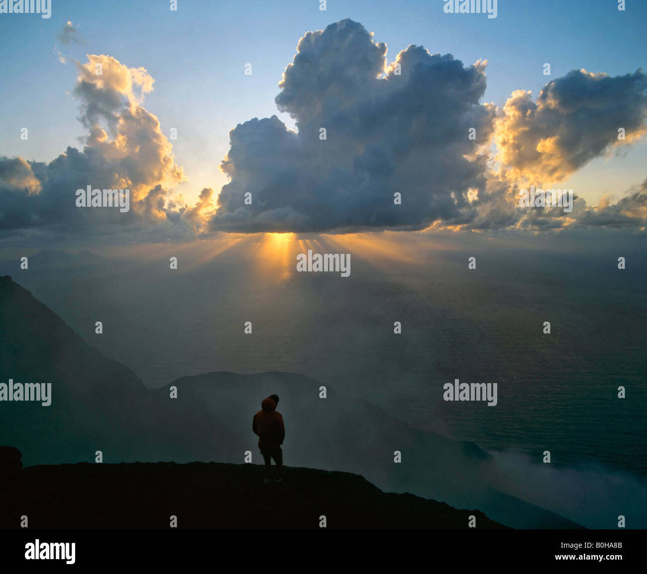 Picco del vulcano Stromboli, man standing in controluce, raggi solari, raggi di luce del sole, isole Eolie, in Sicilia, Italia Foto Stock