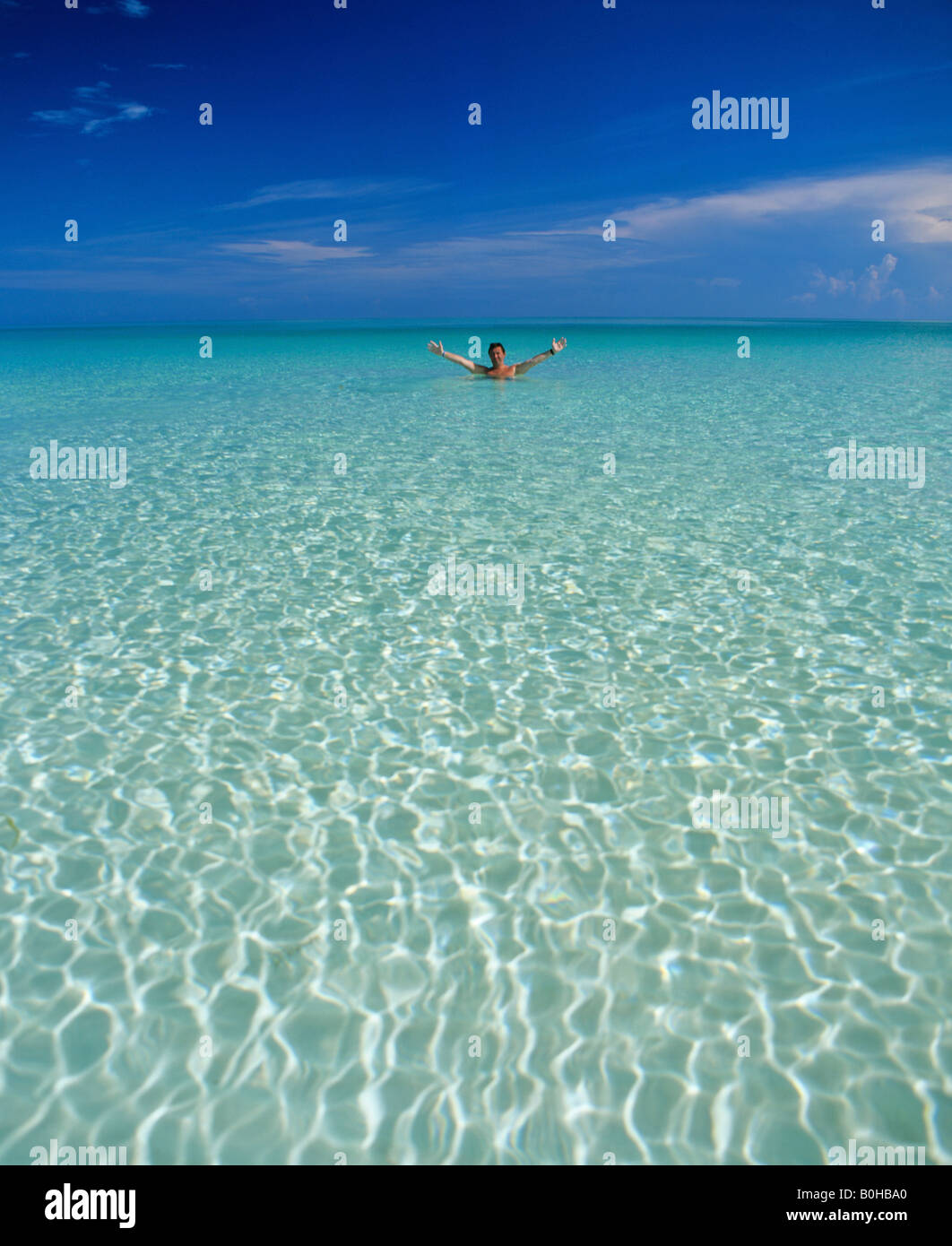 Cristalline acque dell'oceano, l'uomo in piedi in acqua poco profonda, Maldive, Oceano Indiano Foto Stock