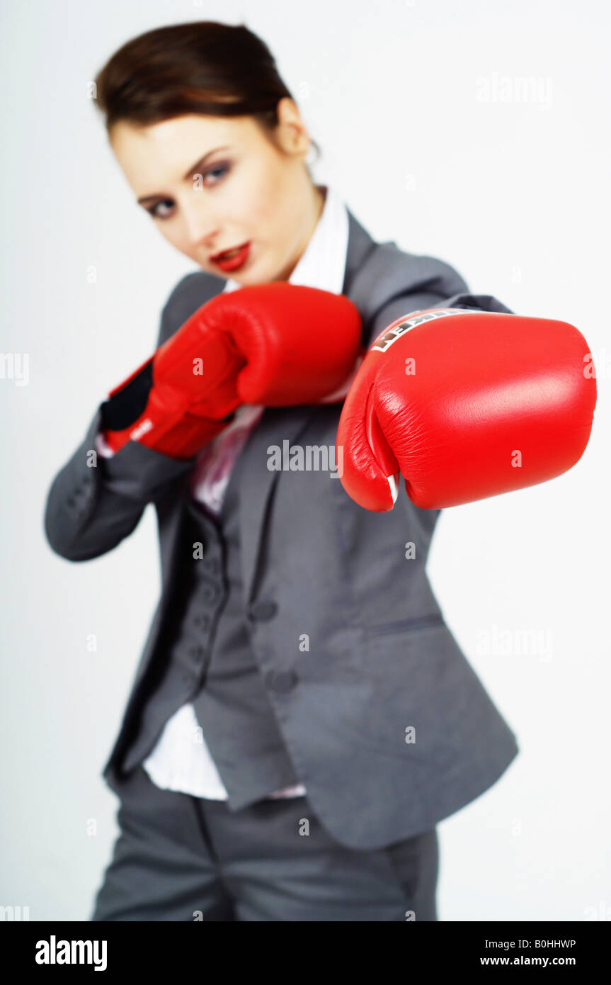 Giovane imprenditrice, manager rosso indossa guantoni da pugilato, punzone in avanti Foto Stock