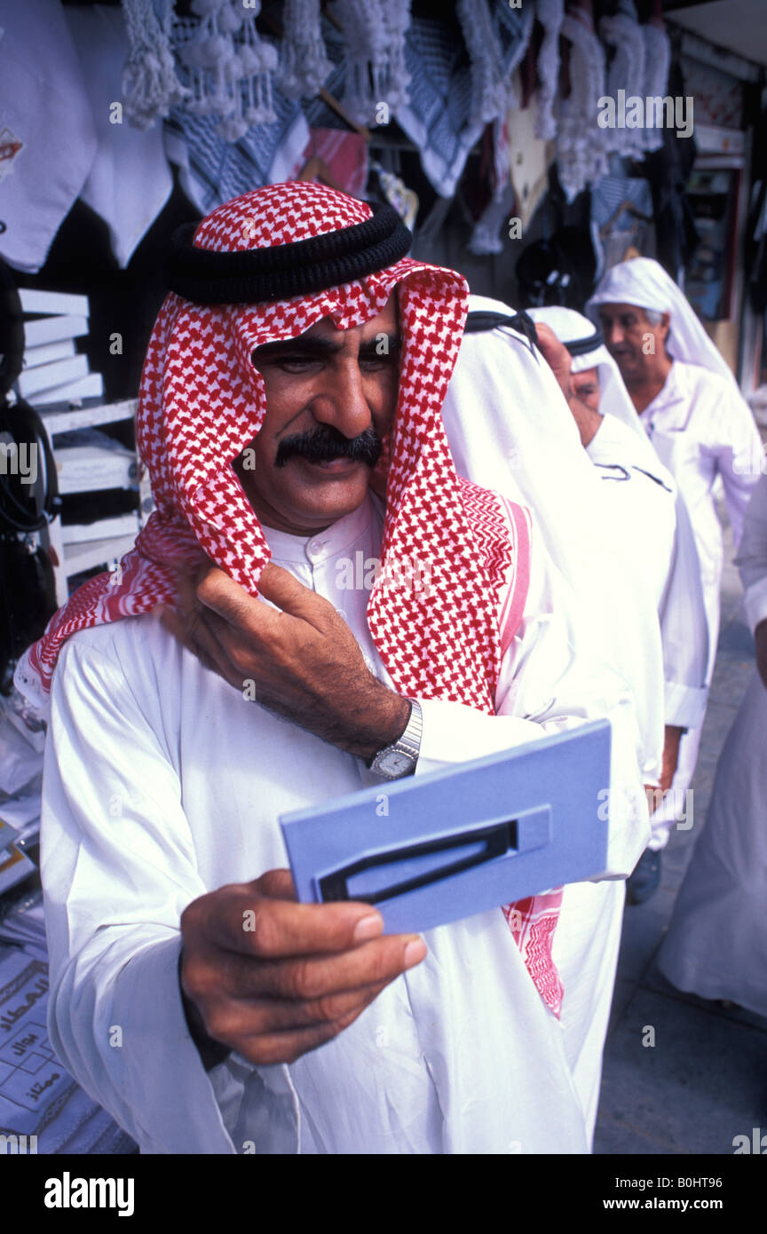 Un uomo arabo il controllo dei suoi copricapo in uno specchio, Amman, Giordania. Foto Stock