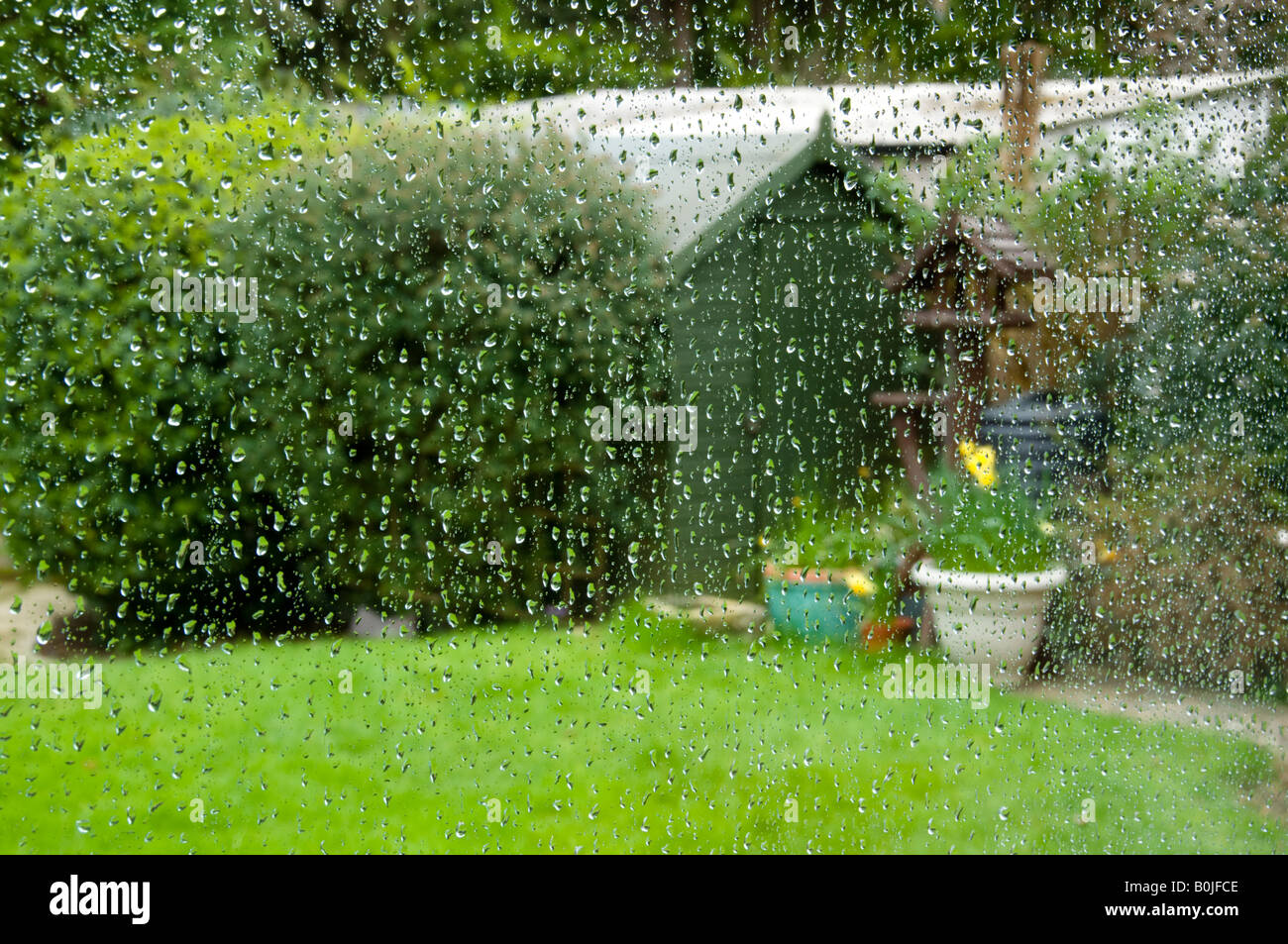 Giardino visto attraverso una finestra in un giorno di pioggia Foto Stock